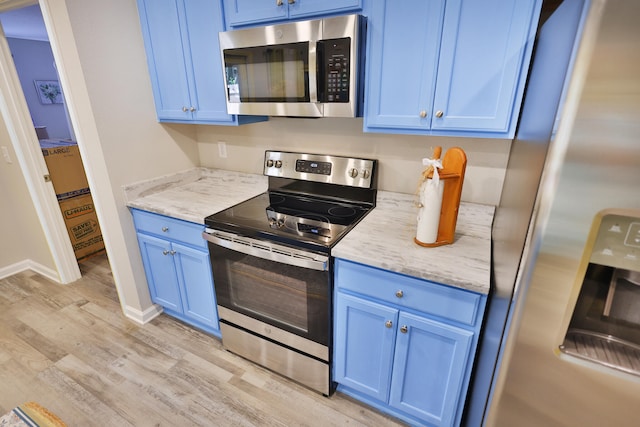 kitchen with light hardwood / wood-style floors, blue cabinets, stainless steel appliances, and light stone counters