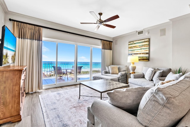 living area with crown molding, visible vents, ceiling fan, a water view, and light wood finished floors