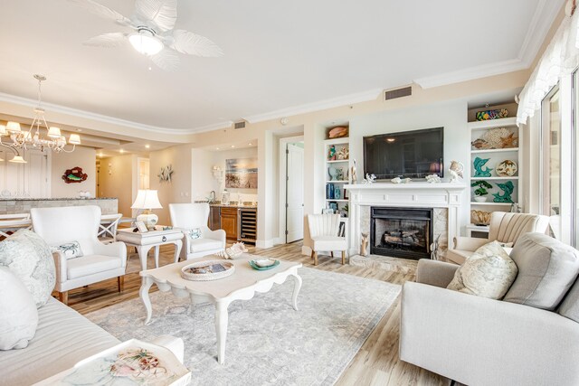 living room featuring built in shelves, light hardwood / wood-style floors, ornamental molding, and beverage cooler