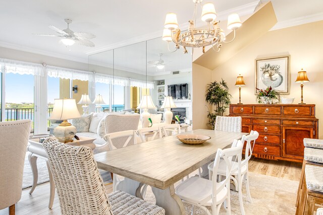 dining space featuring ceiling fan with notable chandelier, crown molding, and light hardwood / wood-style flooring