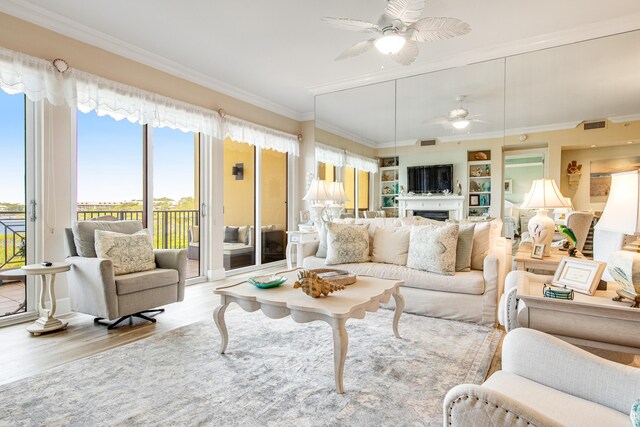 living room with ceiling fan, light hardwood / wood-style floors, built in features, and crown molding