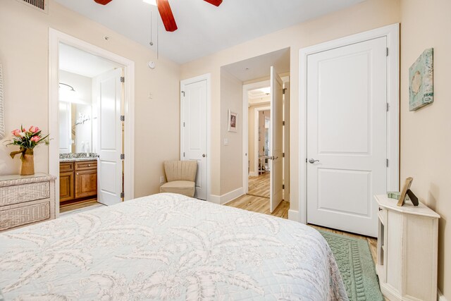 bedroom with ensuite bath, ceiling fan, and light hardwood / wood-style floors