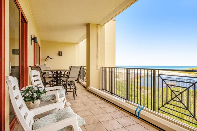 balcony featuring a water view, a view of the beach, and a baseboard heating unit