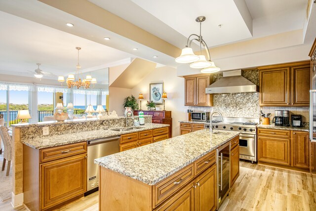 kitchen featuring pendant lighting, a center island with sink, and wall chimney range hood