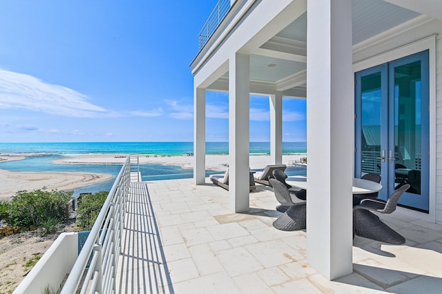 view of patio featuring a water view, a balcony, and a view of the beach