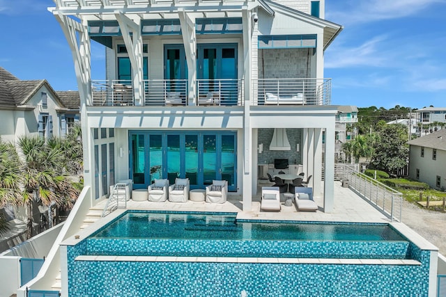 rear view of property featuring a balcony, fence, a fenced in pool, an outdoor living space with a fireplace, and a patio area