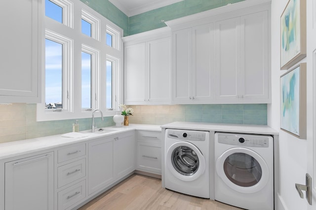 washroom with a sink, light wood-type flooring, washing machine and clothes dryer, and cabinet space