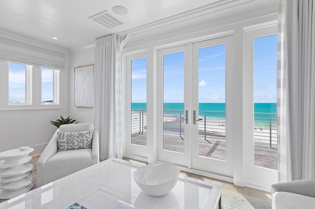 entryway with a view of the beach, french doors, a water view, and visible vents