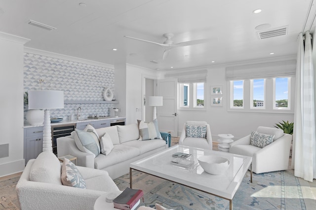 living room with recessed lighting, visible vents, baseboards, a ceiling fan, and ornamental molding