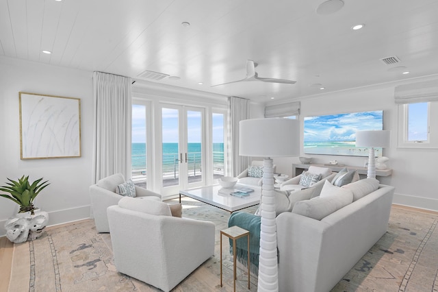 living area with light wood-type flooring, a water view, a beach view, and visible vents