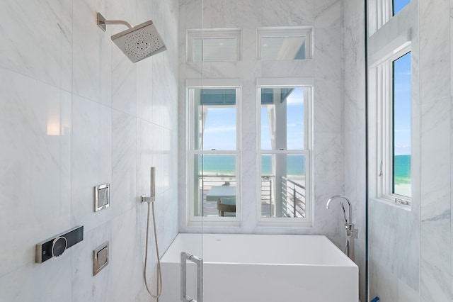 full bath with a water view, a freestanding bath, and tile walls