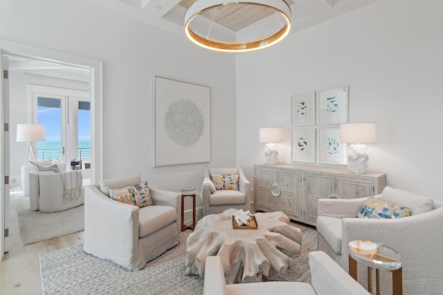 living area with beam ceiling, a water view, and light wood-style flooring