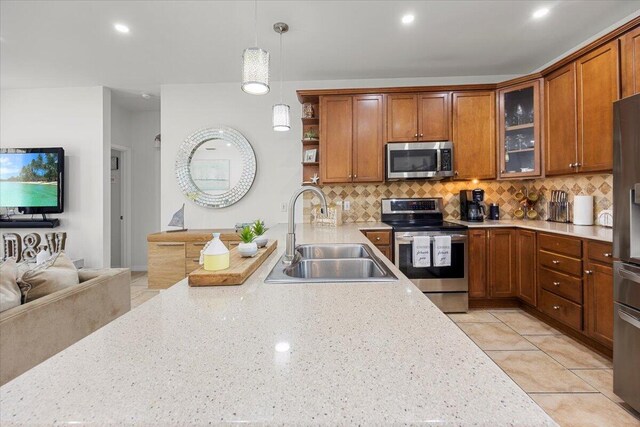 kitchen featuring pendant lighting, sink, stainless steel appliances, light stone countertops, and decorative backsplash