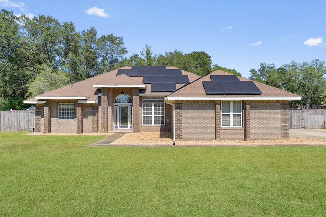 view of front of home with a front yard and solar panels