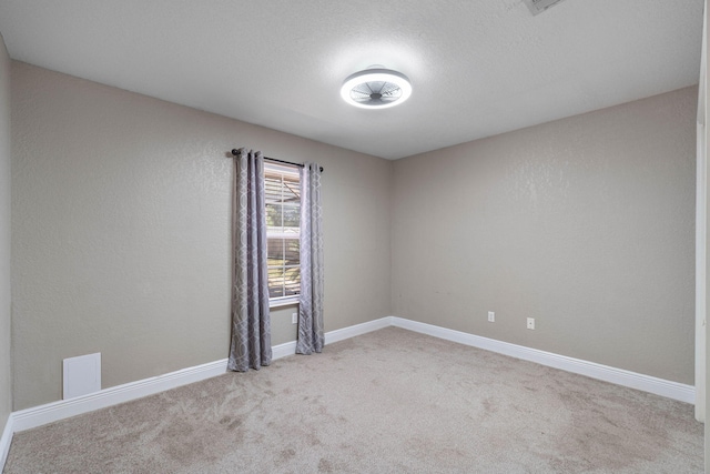 carpeted empty room featuring a textured ceiling