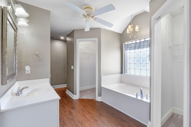 bathroom featuring hardwood / wood-style floors, vaulted ceiling, ceiling fan with notable chandelier, a bath, and vanity