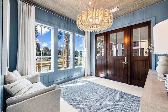 entryway featuring an inviting chandelier, wood walls, and wooden ceiling