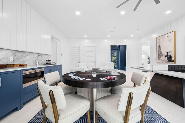 dining space featuring wooden walls, sink, and ceiling fan