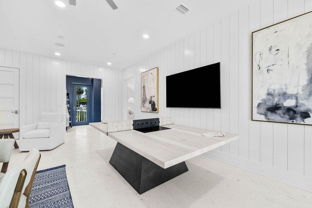 living room with ceiling fan and wood walls