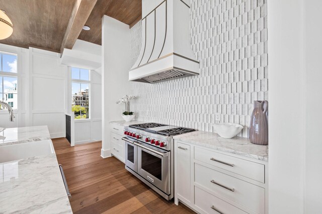 kitchen featuring dark wood-type flooring, white cabinetry, double oven range, light stone countertops, and decorative backsplash