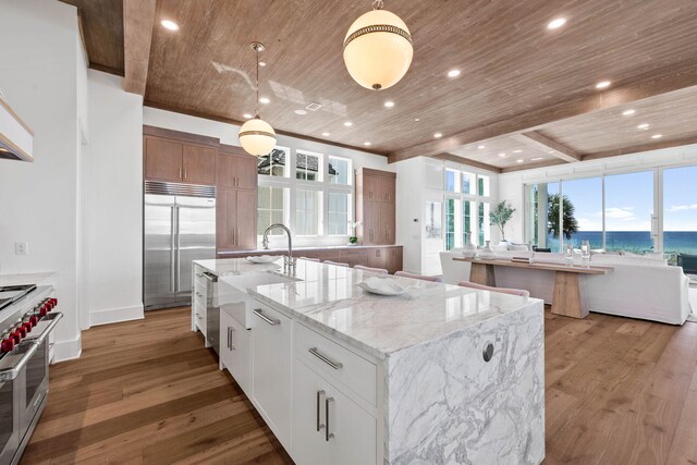 kitchen featuring a large island with sink, white cabinetry, premium appliances, wooden ceiling, and wood-type flooring