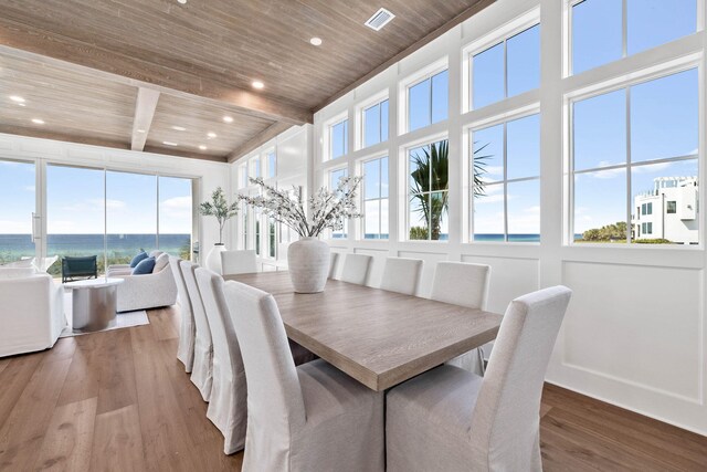 dining space featuring wooden ceiling, a water view, beamed ceiling, and hardwood / wood-style flooring