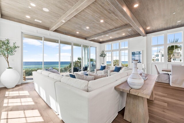 living room with wood ceiling, a water view, and a healthy amount of sunlight