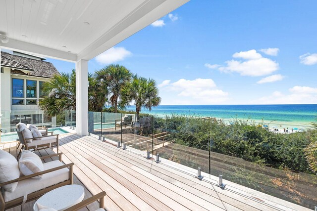 wooden deck with a beach view, a water view, and outdoor lounge area