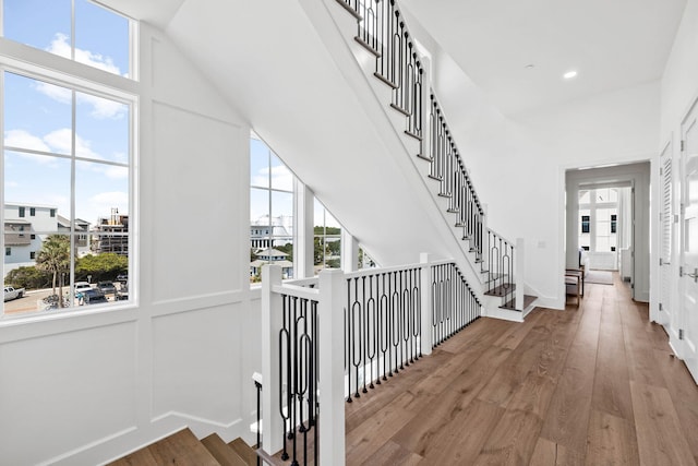 stairway featuring wood-type flooring, a high ceiling, and plenty of natural light