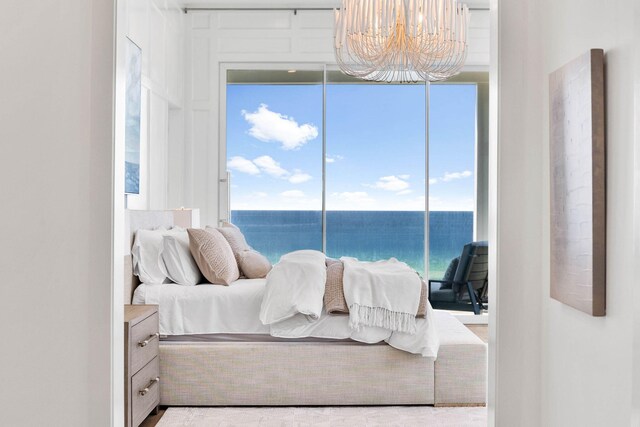 bedroom featuring an inviting chandelier, a water view, and access to outside