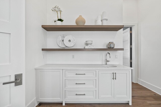 bar featuring white cabinetry, sink, and dark wood-type flooring