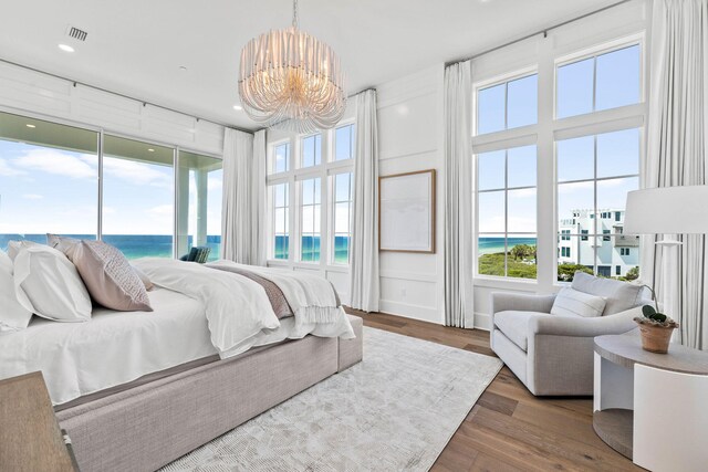 bedroom with hardwood / wood-style flooring, a chandelier, and a water view