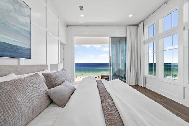 bedroom featuring a view of the beach, a water view, and hardwood / wood-style flooring