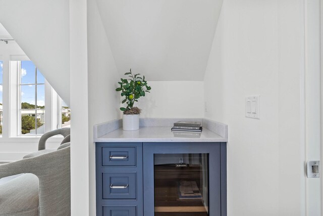 interior space featuring lofted ceiling, beverage cooler, and blue cabinetry