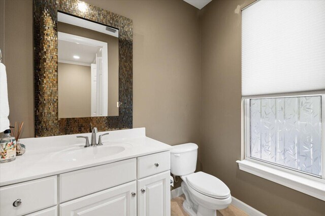 bathroom featuring ornamental molding, vanity, and toilet