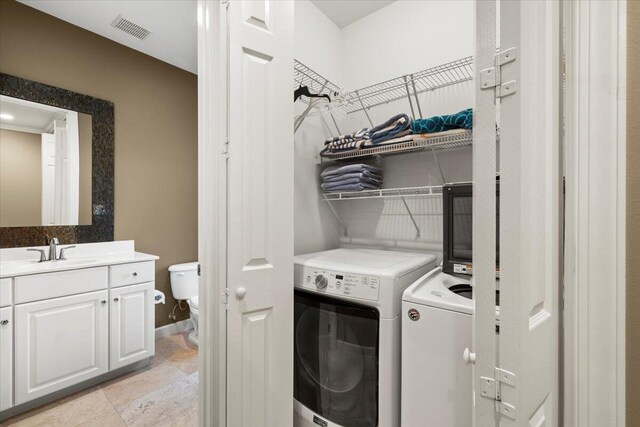 clothes washing area featuring light tile patterned floors, sink, and washer and dryer