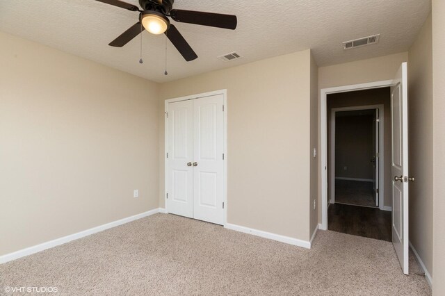 unfurnished bedroom featuring a textured ceiling, ceiling fan, and light colored carpet