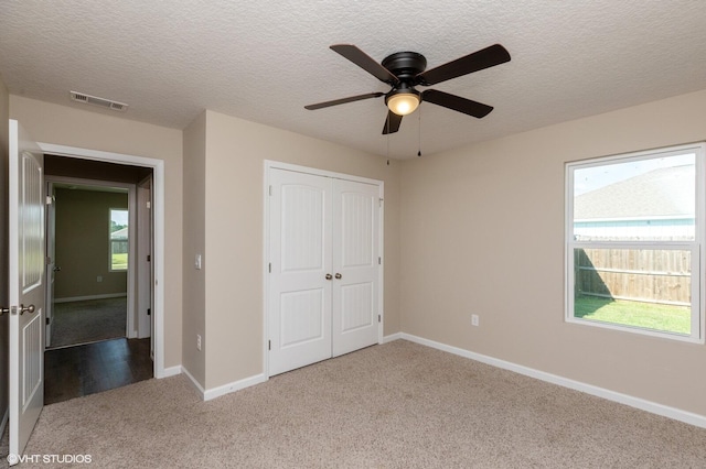 unfurnished bedroom with a closet, light colored carpet, ceiling fan, and a textured ceiling