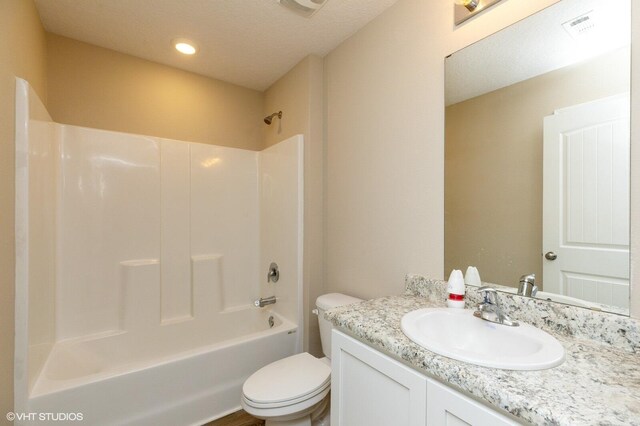 full bathroom with bathtub / shower combination, a textured ceiling, vanity, and toilet