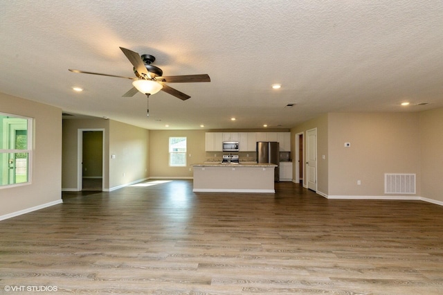 unfurnished living room with ceiling fan, a textured ceiling, and light hardwood / wood-style flooring