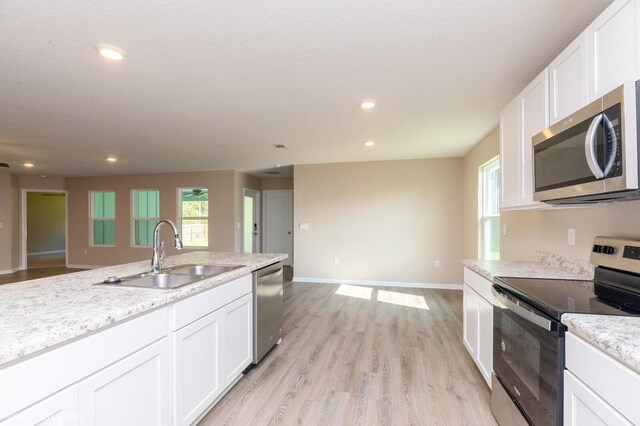 kitchen with stainless steel appliances, white cabinetry, light hardwood / wood-style floors, and sink