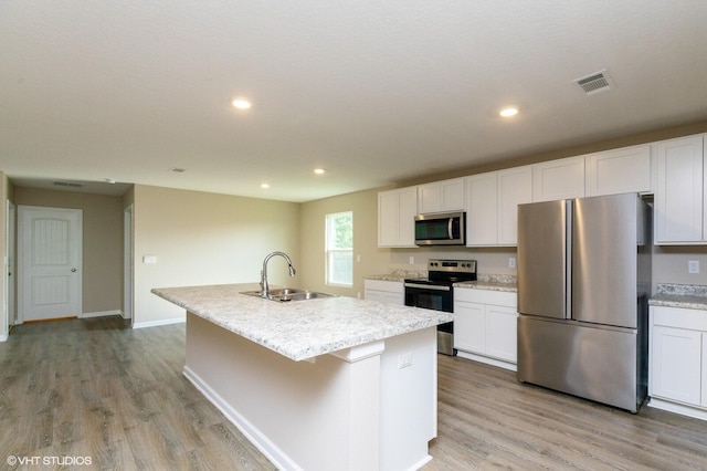 kitchen with a kitchen island with sink, appliances with stainless steel finishes, sink, and white cabinetry