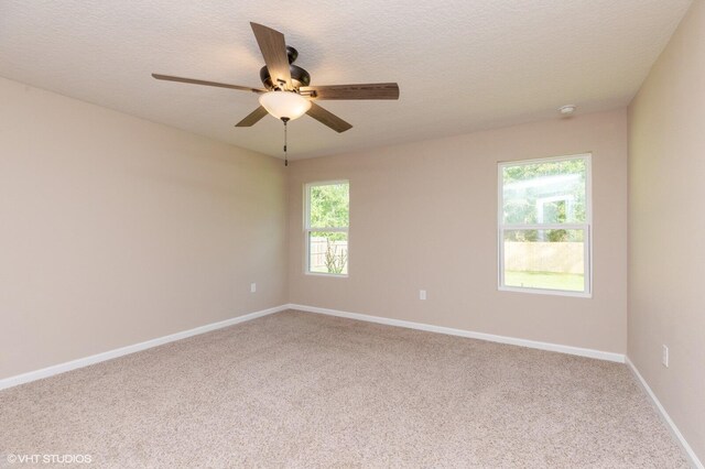 carpeted spare room featuring ceiling fan, a textured ceiling, and plenty of natural light