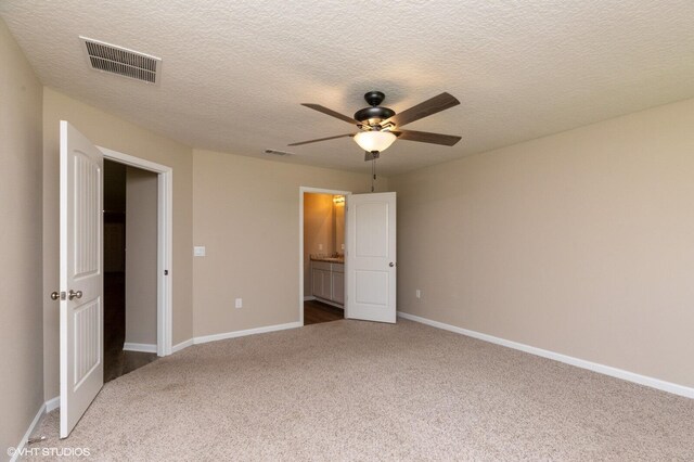 unfurnished bedroom with connected bathroom, ceiling fan, carpet flooring, and a textured ceiling