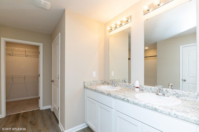 bathroom with a textured ceiling, wood-type flooring, and vanity