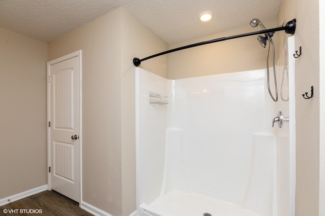 bathroom with walk in shower, wood-type flooring, and a textured ceiling