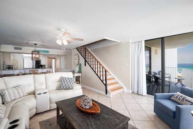 tiled living room featuring a water view and ceiling fan with notable chandelier