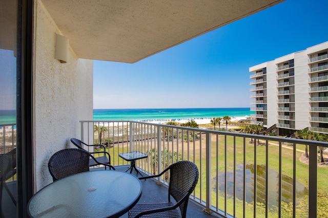 balcony with a water view and a view of the beach