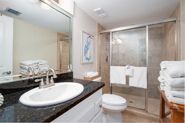 bathroom with toilet, a textured ceiling, walk in shower, and vanity