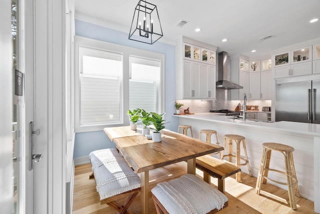 dining space featuring crown molding, sink, light hardwood / wood-style flooring, and a notable chandelier